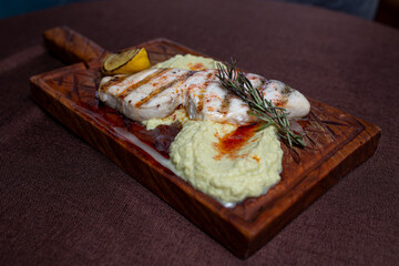 Grilled fish fillet with lemon and herb butter on a wooden board
