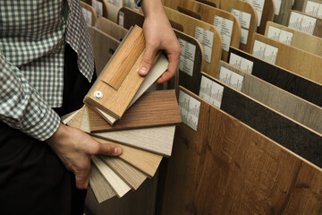 Man with samples of wooden flooring in shop, closeup