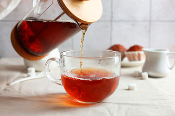 Pouring warm tea into cup on light table, closeup