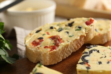 Tasty butter with olives, chili pepper, parsley and bread on table, closeup