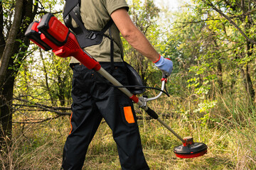 Man using a brush cutter to clear bushes - 796792265