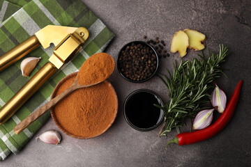 Aromatic spices, fresh ingredients for marinade and garlic press on brown table, flat lay