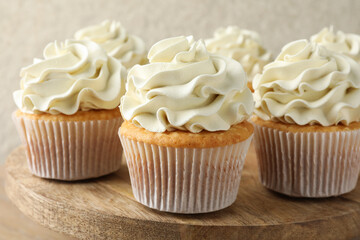 Tasty vanilla cupcakes with cream on table, closeup