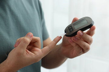 Diabetes test. Man checking blood sugar level with glucometer at home, closeup