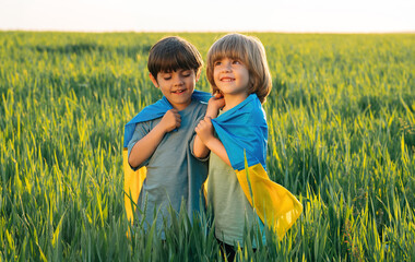 Happy glad boys - Ukrainian patriots children with national flag on in fresh green field.