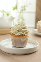 Tasty cupcake with vanilla cream on light wooden table, closeup