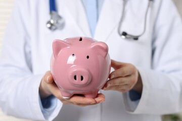 Doctor with pink ceramic piggy bank, closeup