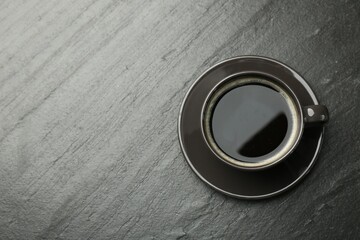 Hot coffee in cup on dark textured table, top view. Space for text