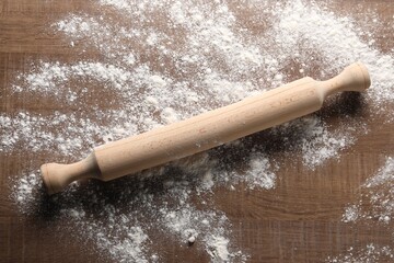 Scattered flour and rolling pin on wooden table, top view