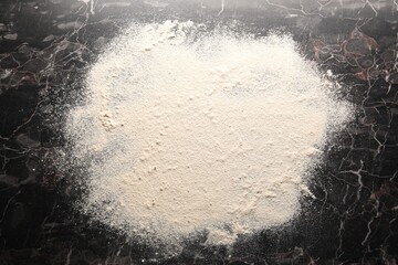 Pile of flour on black marble table, top view