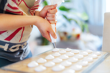 Close up man placing batter on silicone baking sheet to make French macaroons dessert in light modern kitchen at home. Preparing steps for baking cookies. Culinary hobby. Selective focus