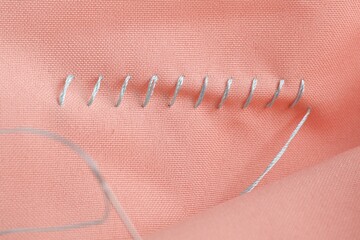 Sewing thread and stitches on coral cloth, top view