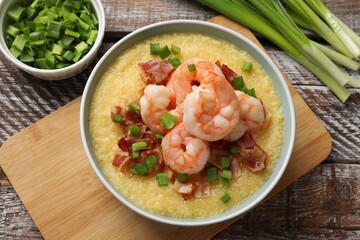 Fresh tasty shrimps, bacon, grits and green onion in bowl on wooden table, flat lay