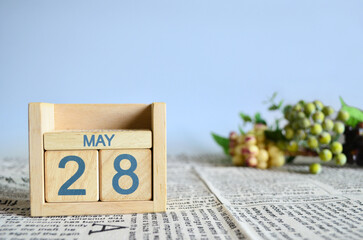 May 28, Calendar cover design with number cube with fruit on newspaper fabric and blue background.