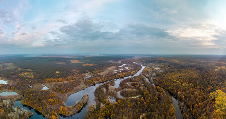 Aerial autumn river valley panorama with colorful wooded riverbanks and scenic sky in Ukraine