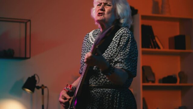 Eccentric rock-n-roll granny playing electric guitar and singing a favorite song