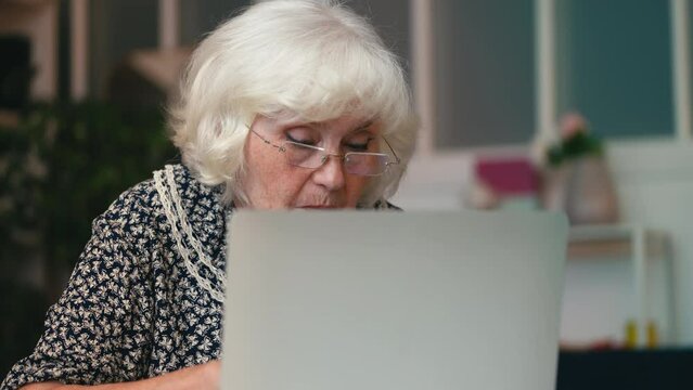 Contemporary granny booking a hotel on laptop, successfully sending an e-mail