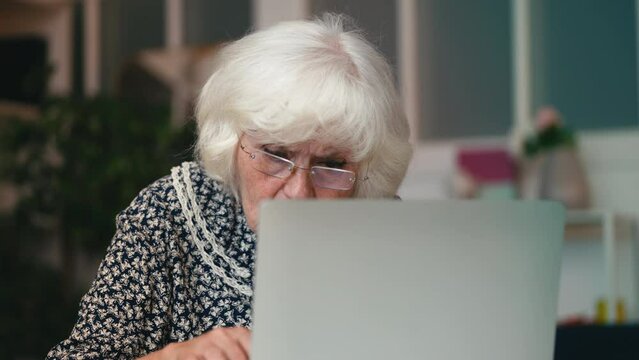 Shocked elderly woman having problems with laptop, phishing or spam, hacking