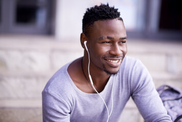 Outdoor, earphones and black man in campus, smile and listening to audio, radio and music in...