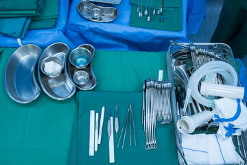 Surgical clamps and medical equipment on green surgical tray inside operating room.Sterile surgical...