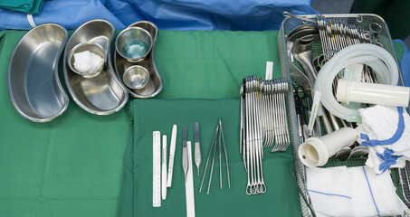 Surgical clamps and medical equipment on green surgical tray inside operating room.Sterile surgical...