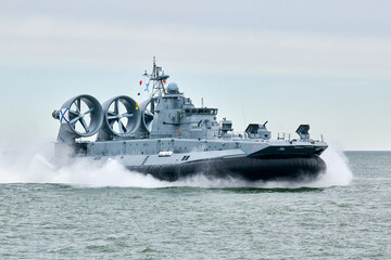 Hovercraft warship armed with armament sails into sea toward military target to attack and destroy...
