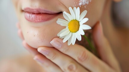 A chamomile flower used as a natural skincare treatment, applied to a person's face.