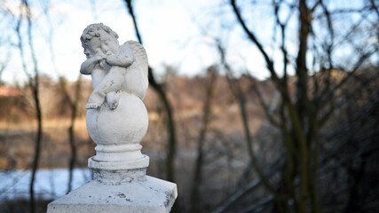 angel statue in the park. little boy with wings. cupid statue in autumn park. figurine for design,...