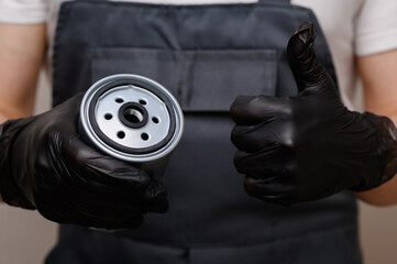 Fuel filter for diesel cars in male hands, close-up. Auto mechanic showing thumbs up gesture....