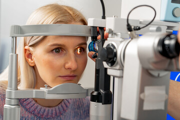 close up in an ophthalmology clinic young doctor diagnoses the eyes of a young girl with a...