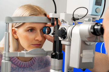 close up in an ophthalmology clinic young doctor diagnoses the eyes of a young girl with a...