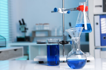 Laboratory analysis. Flasks and beaker with blue liquid on white table indoors