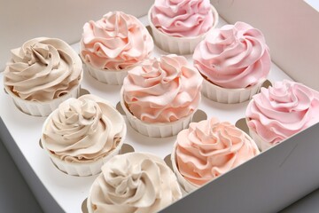 Many tasty cupcakes with colorful cream in box, closeup