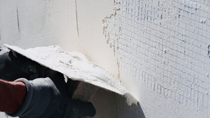 Man at work put mortar on top mesh to plaster interior construction site wall with protective...