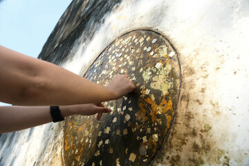 Someone Buddhist Gold leaf is being attached to the soles of feet Reclining Buddha statue.