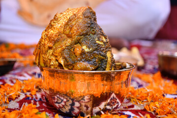 Picture of a large cooked cuttlefish head on the bell-metal bowl Indian meal (Thali) decorated by...