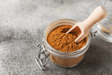Cinnamon powder on a textured wooden background. Spicy spice for baking, desserts and drinks....