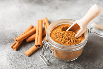 Cinnamon powder on a textured wooden background. Spicy spice for baking, desserts and drinks. Fragrant ground cinnamon. Cinnamon stick. Place for text. Copy space.
