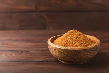 Cinnamon powder on a textured wooden background. Spicy spice for baking, desserts and drinks....
