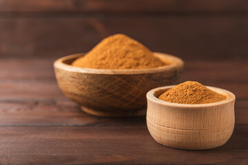 Cinnamon powder on a textured wooden background. Spicy spice for baking, desserts and drinks. Fragrant ground cinnamon. Cinnamon stick. Place for text. Copy space.