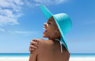 Happy woman wearing sun hat in hot summer beach, enjoying a holiday by the sea. Seen from behind,...