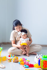 Mother and child playing with children's toys in the house,Mother and child are on the floor in the living room and play with her little child. The child likes to play very much. Around them are child