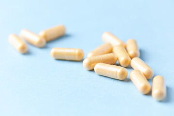 Coenzyme Q10 capsules. Dietary supplements. Blue paper background. Close up.
