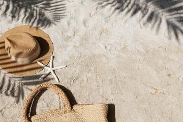 Summer vibes. Straw hat and beach bag on a beautiful white sand. Copy space for text.