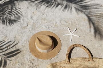 Summer vibes. Straw hat and beach bag on a beautiful white sand. Copy space for text.