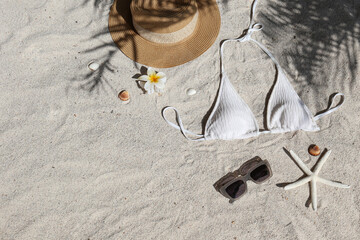 Summer vibes. Straw hat, bathing suit and sunglasses on a sandy beach.. Flat lay, copy space, top...