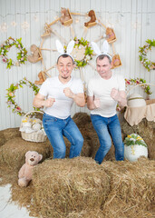 Two man with rabbit ears having fun standing in the haystack
