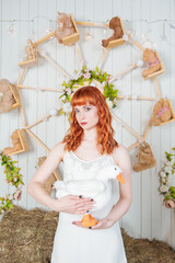 Beautiful redhaired woman with goose toy standing on the haystack Easter holiday concept