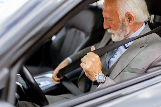 Elderly gentleman buckling up in his luxury car before a drive
