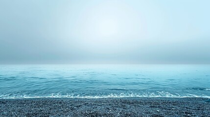   A large body of water rests atop a sandy shore, its edge lapped by gentle waves that consistently ebb and flow - obrazy, fototapety, plakaty